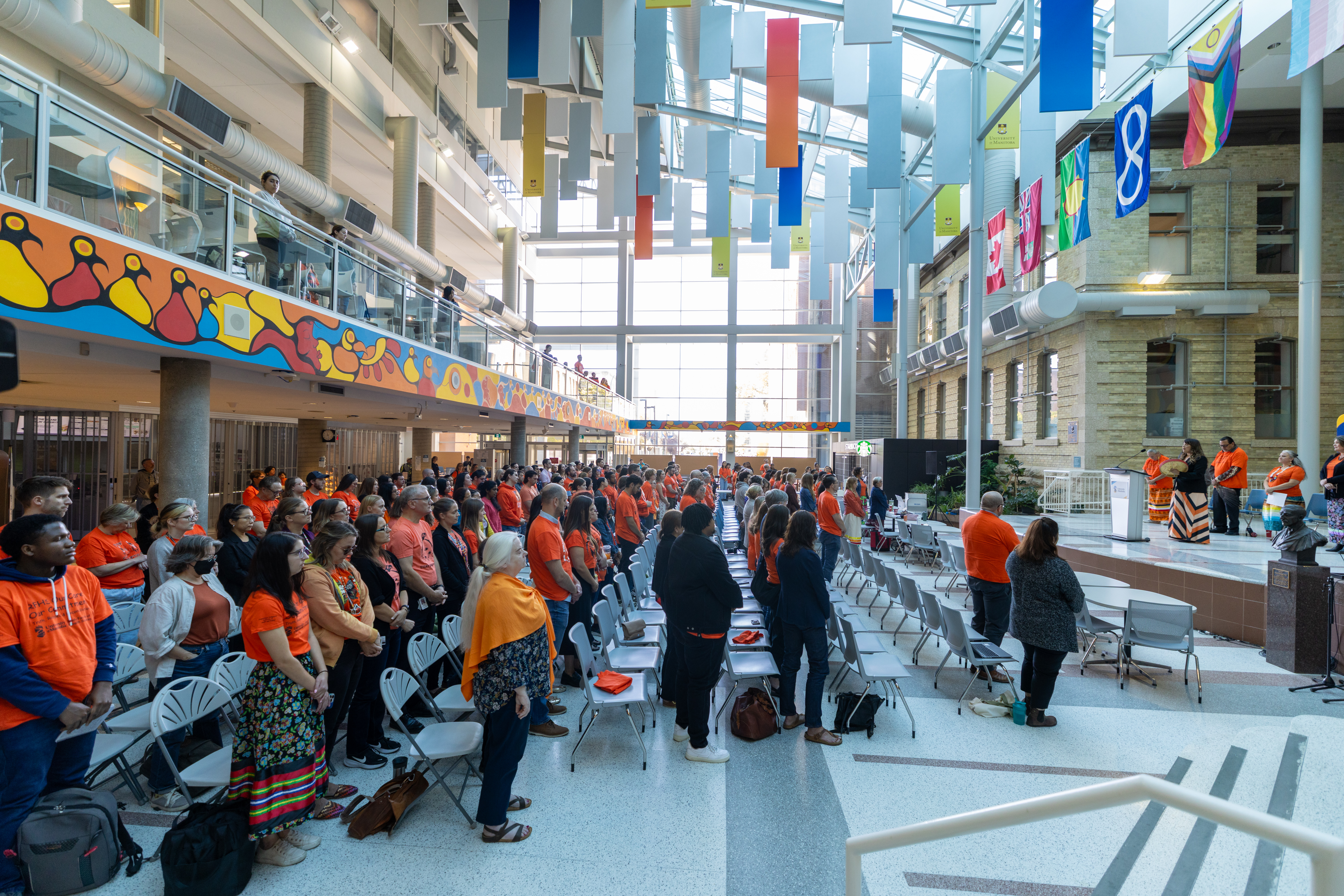 A wide shot of the crowd gathered in the Brodie Atrium, with the stage and speakers visible on the right.