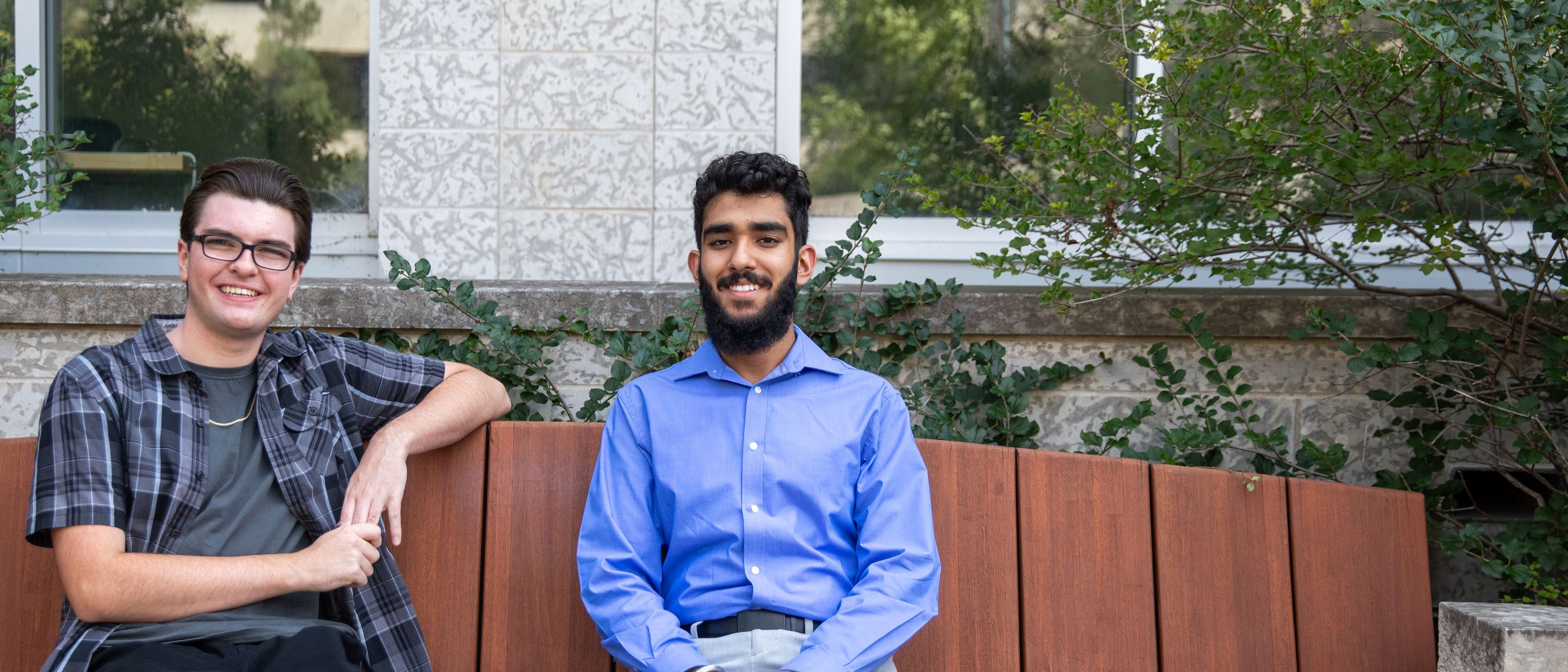 Cody McDonald and Simar Ubhi sit on a bench on UM's Fort Garry Campus