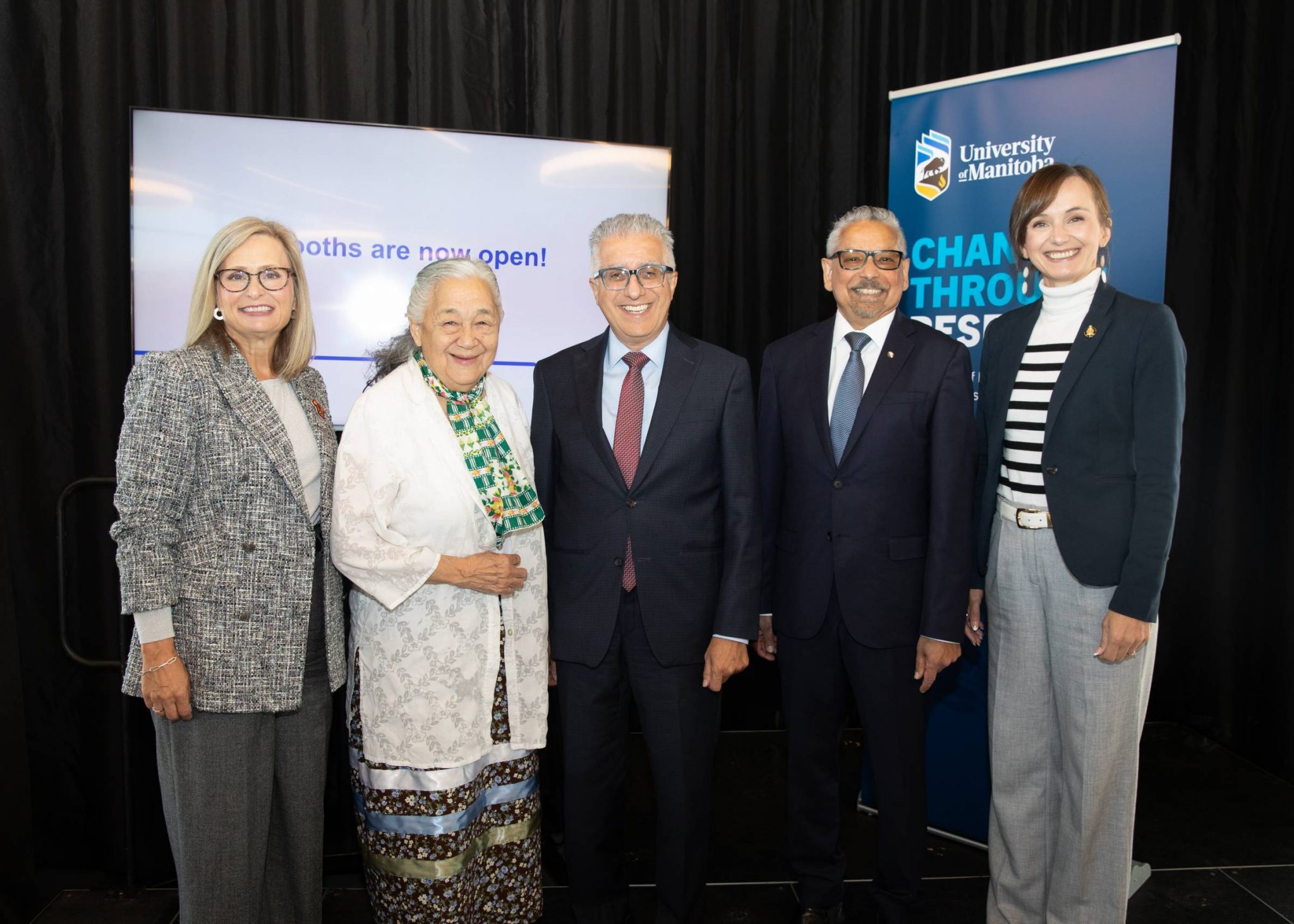 Executives from the University pose together on a stage.