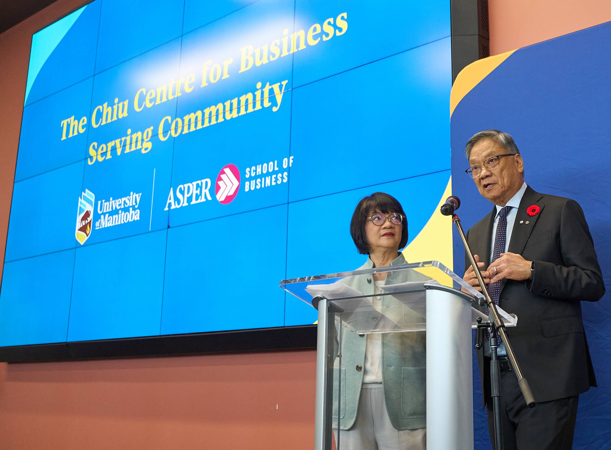 Elanor and Wayne Chiu speaking at a podium.