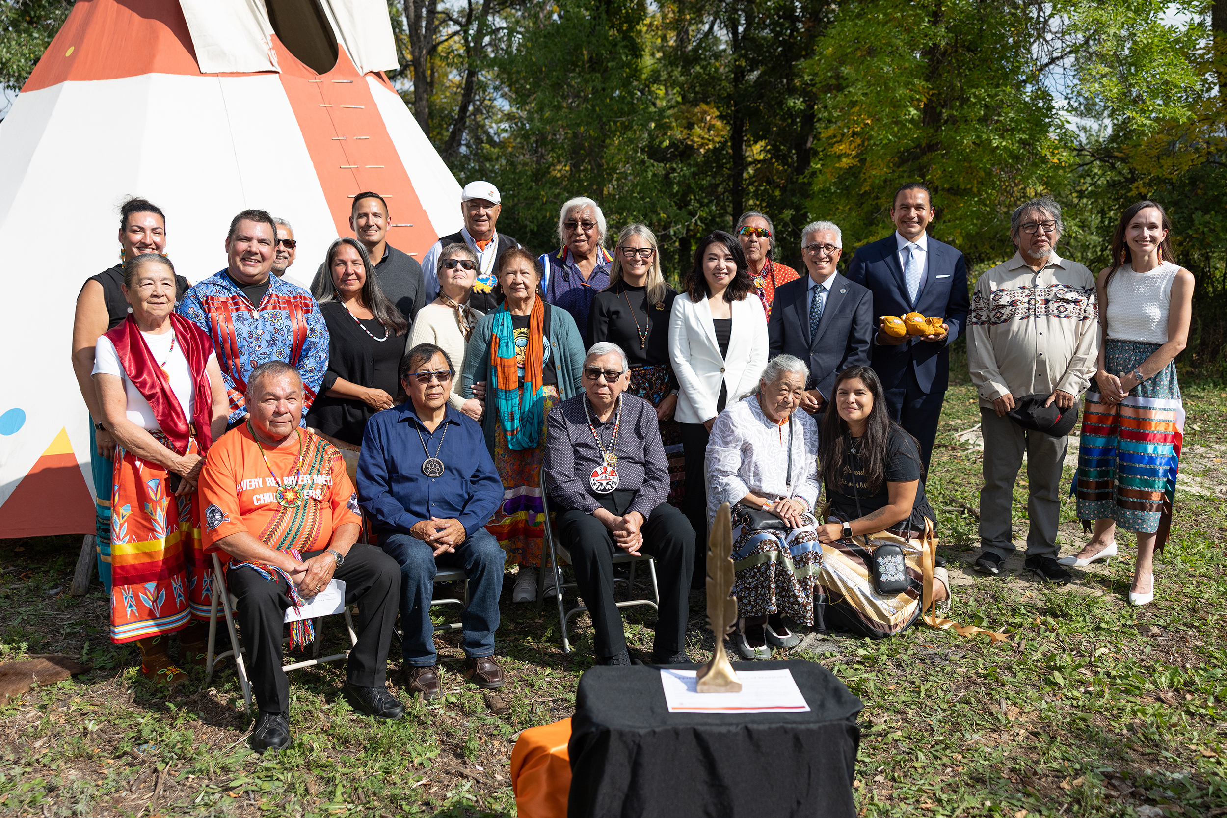 Group of Elders, Survivors, NCTR staff and UM staff outside in front of a teepee