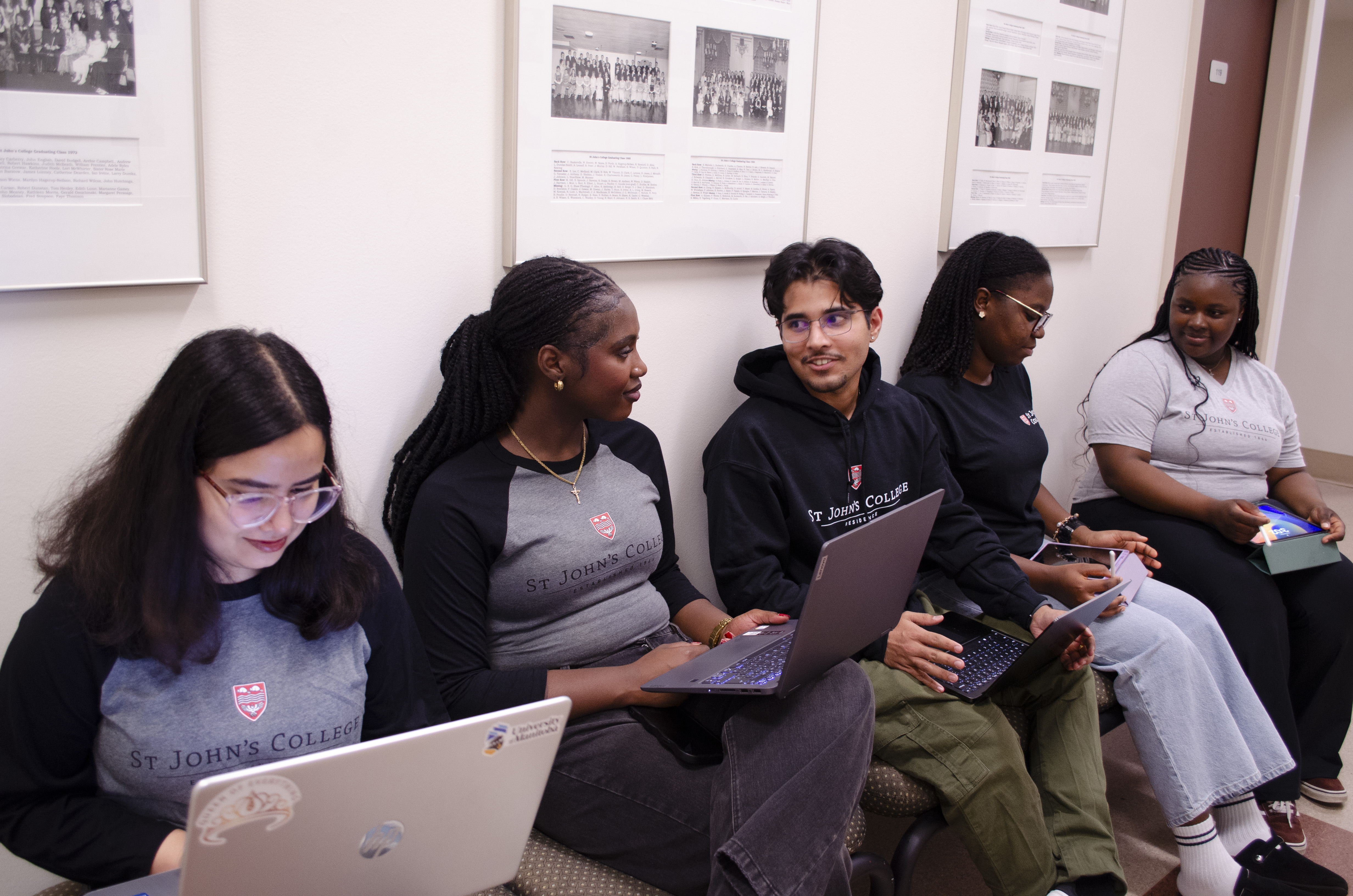 Students sitting on a bench with their laptops