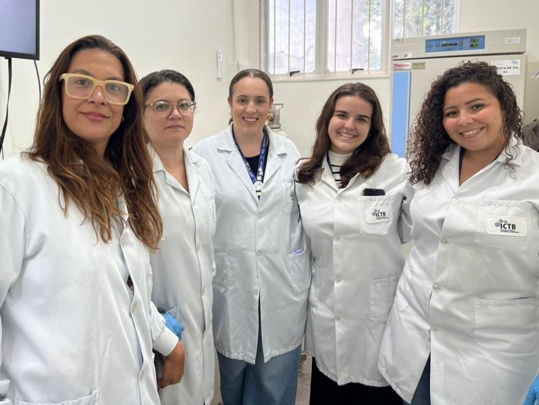 Five people wearing lab coats pose for a photo. 