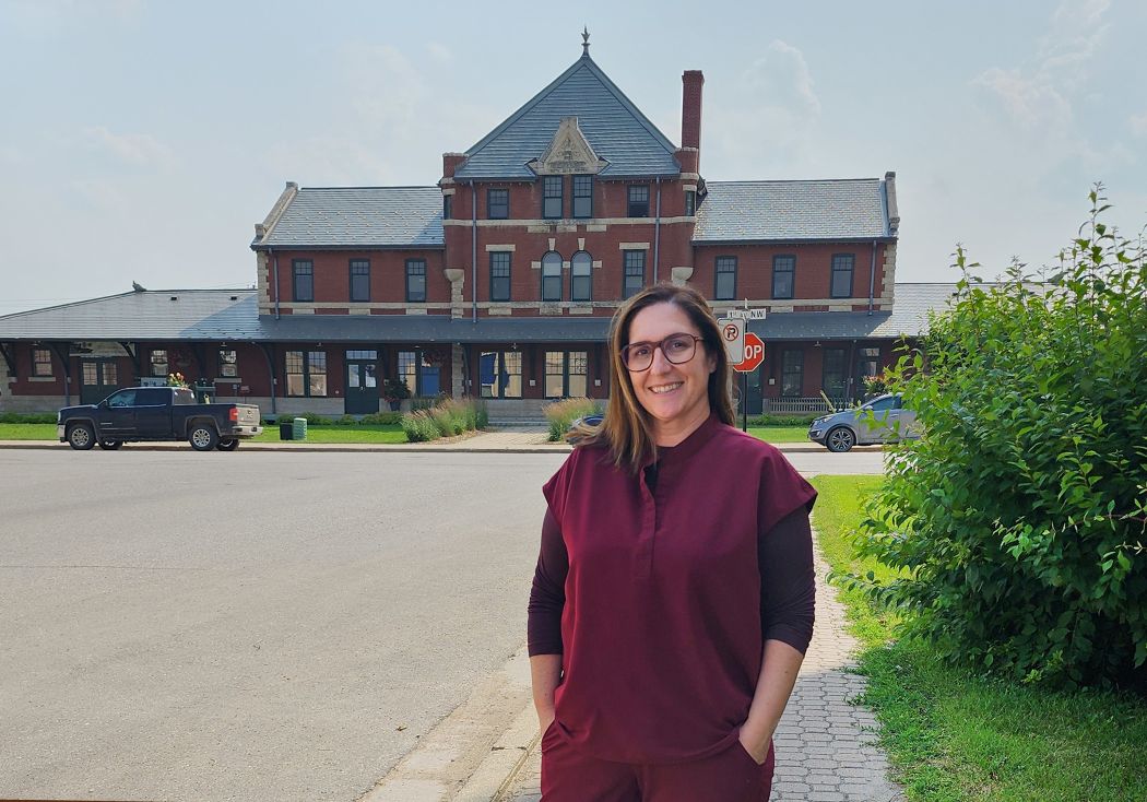 Dr. Daron Baxter stands in front of an old train station in Dauphin, Manitoba.