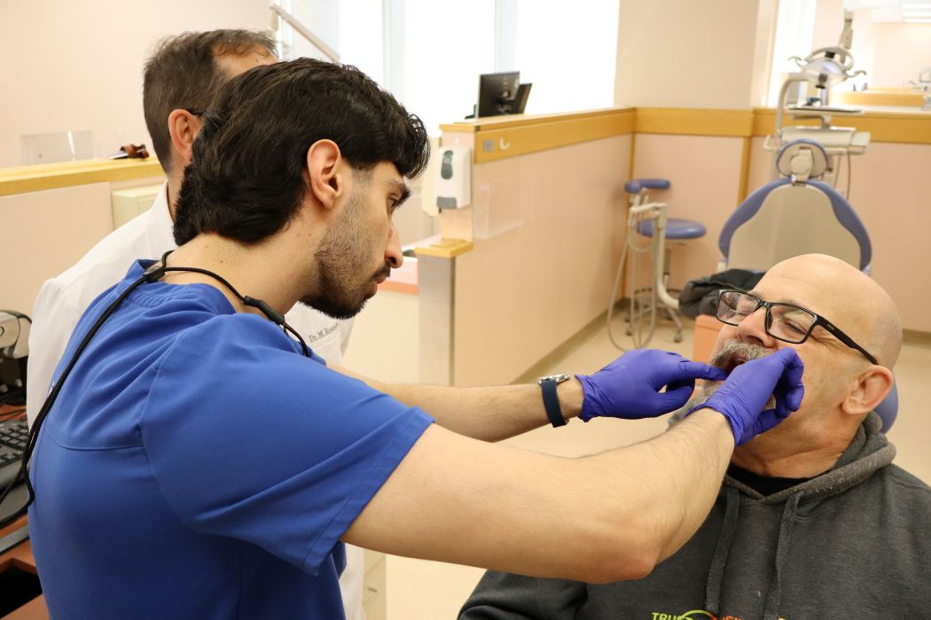 A dental student looks into a patient's mouth in a dental clinic. 