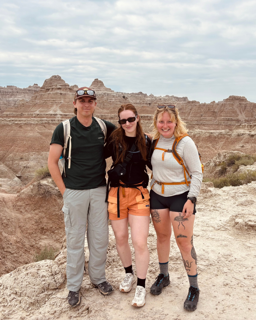 A grou pof three people stand at a look out point on a scenic hike.