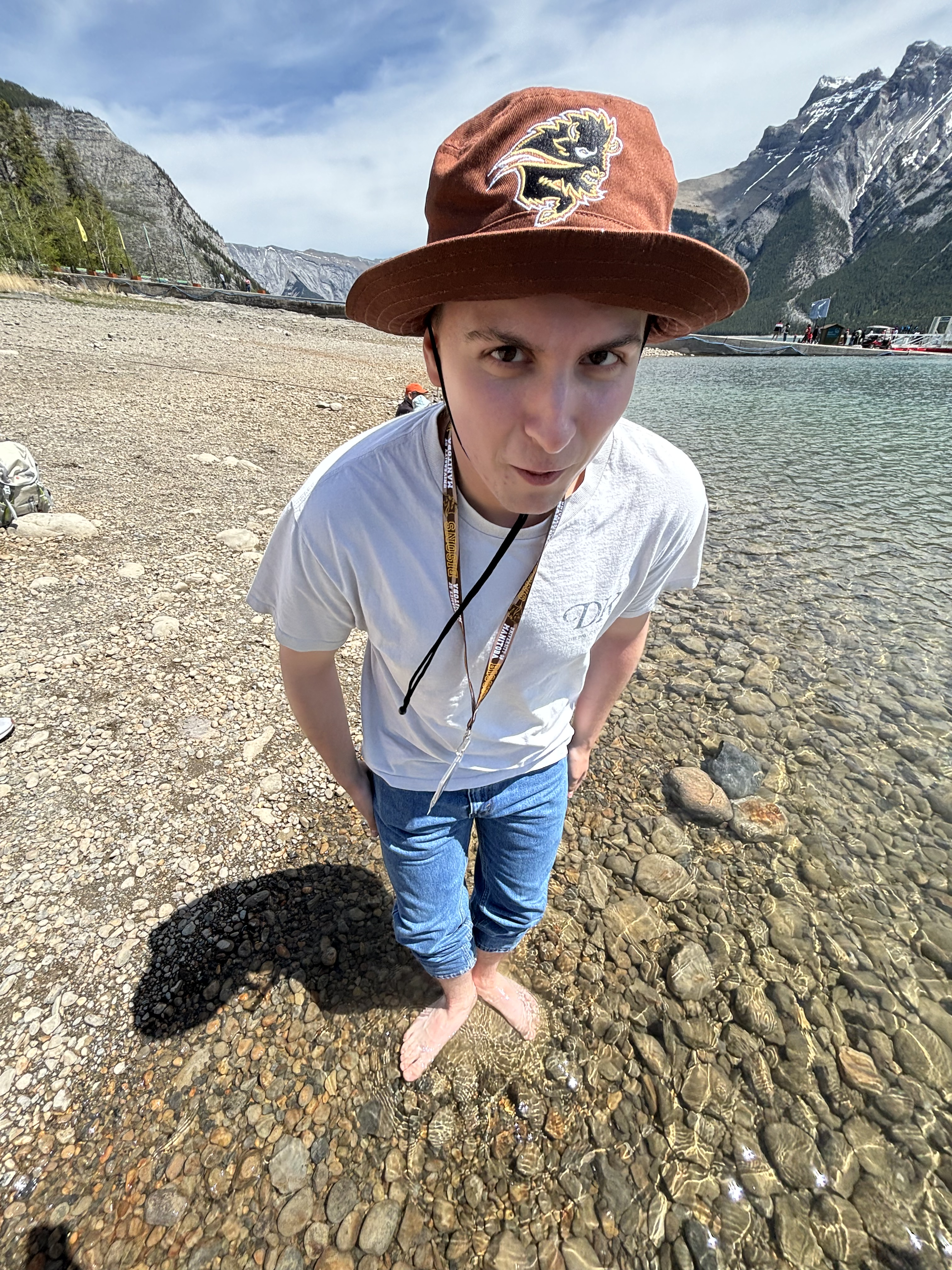 A young man stands in a river in the mountains.