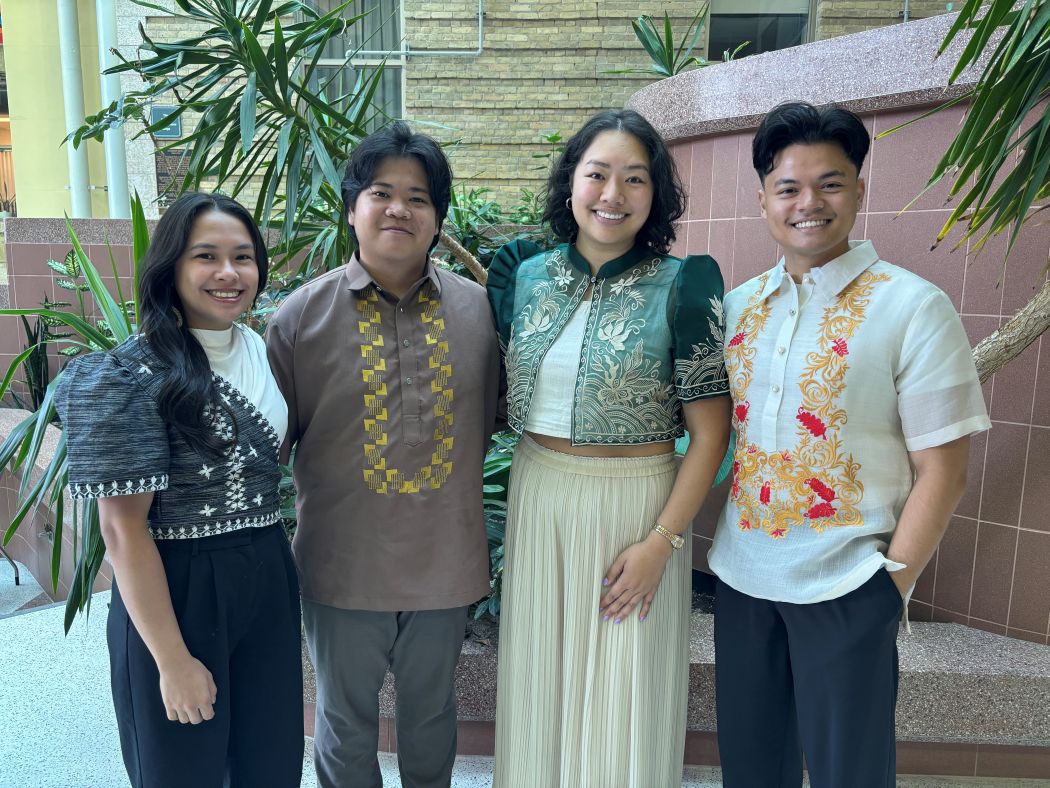 Four people wearing traditional Filipino clothing pose for a photo. 