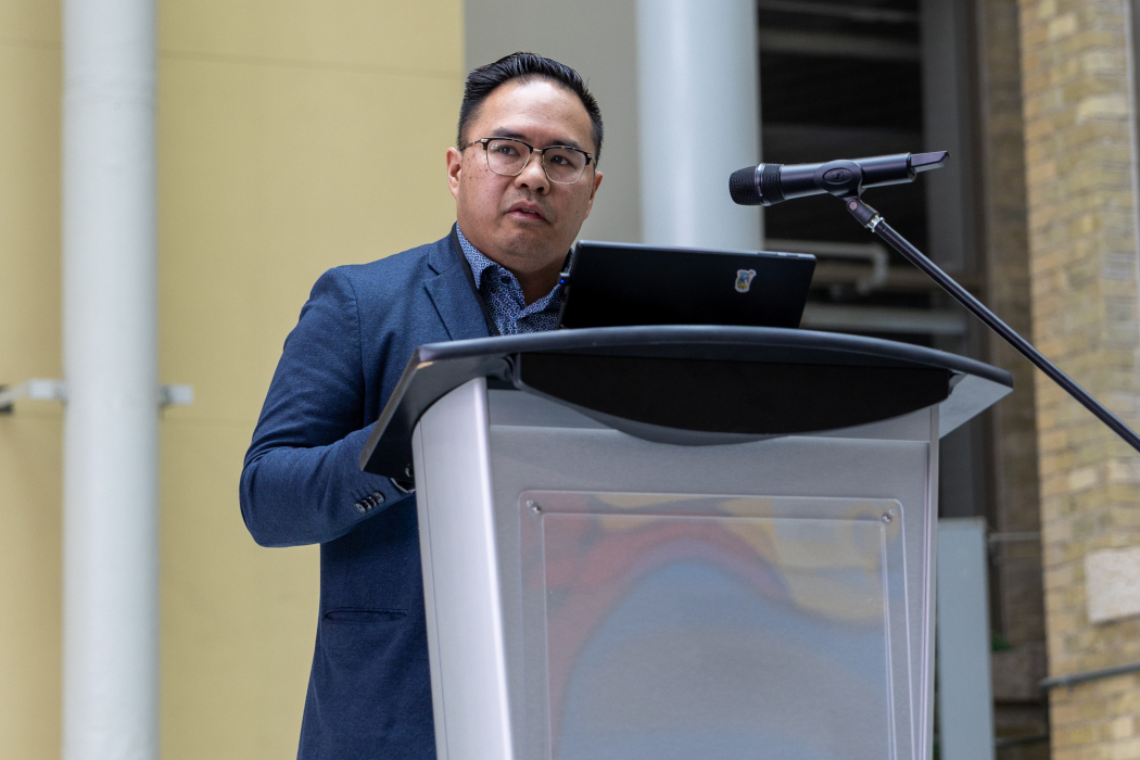 Dr. Cesar Rona speaks at a lectern. 