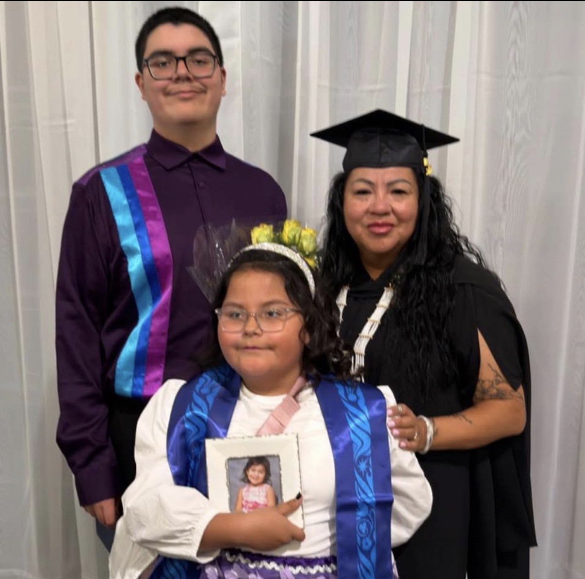 Glennis Bird celebrates graduation with her children Colton, Bella, and appearing in a photograph, the late Chloe Bushie.