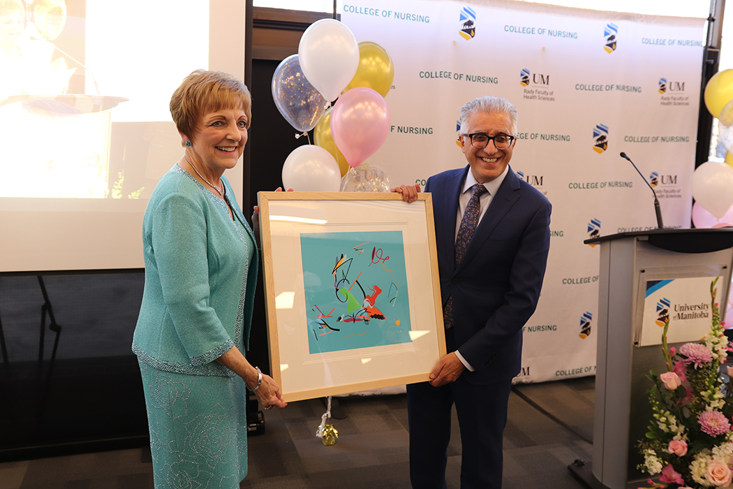 A man and a woman hold a framed painting.