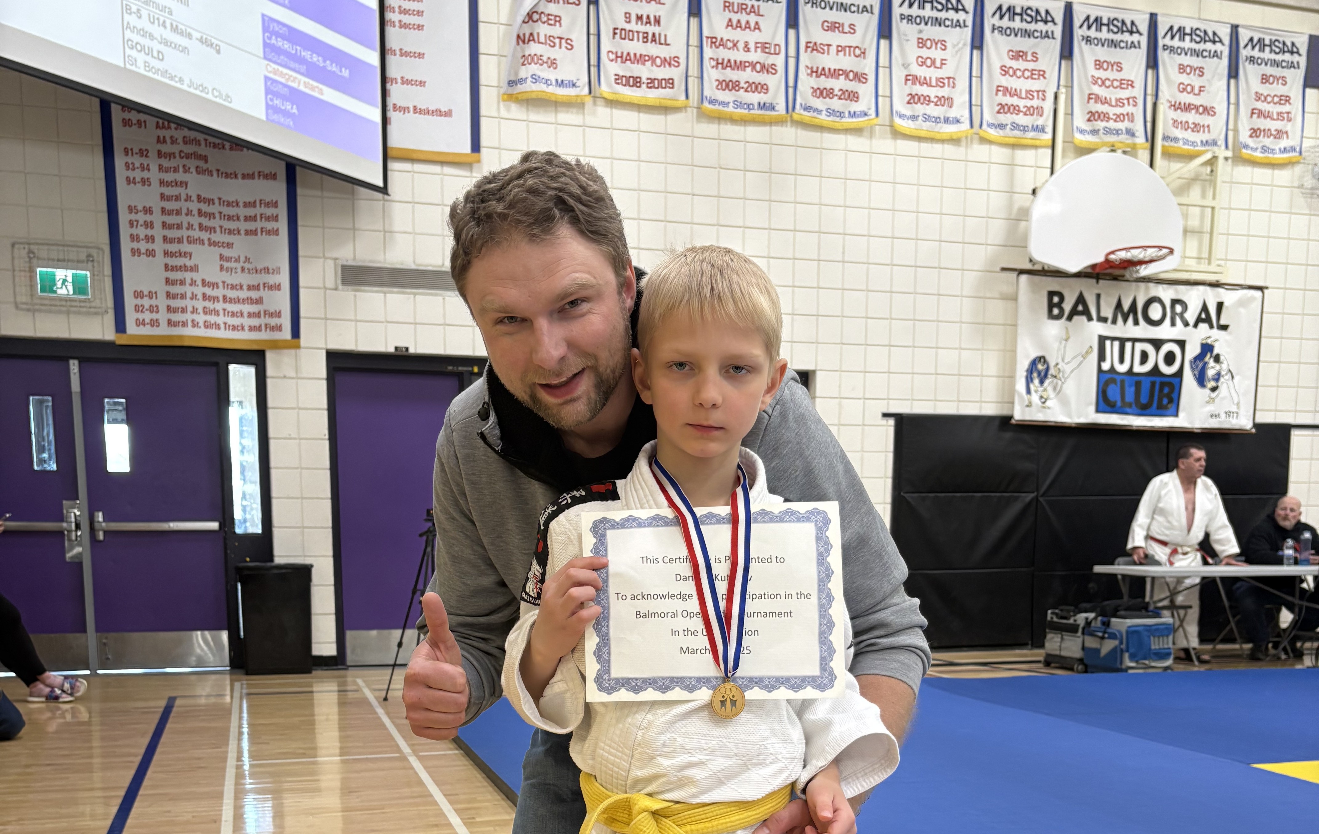a father gives a thumbs-up to the camera with his son