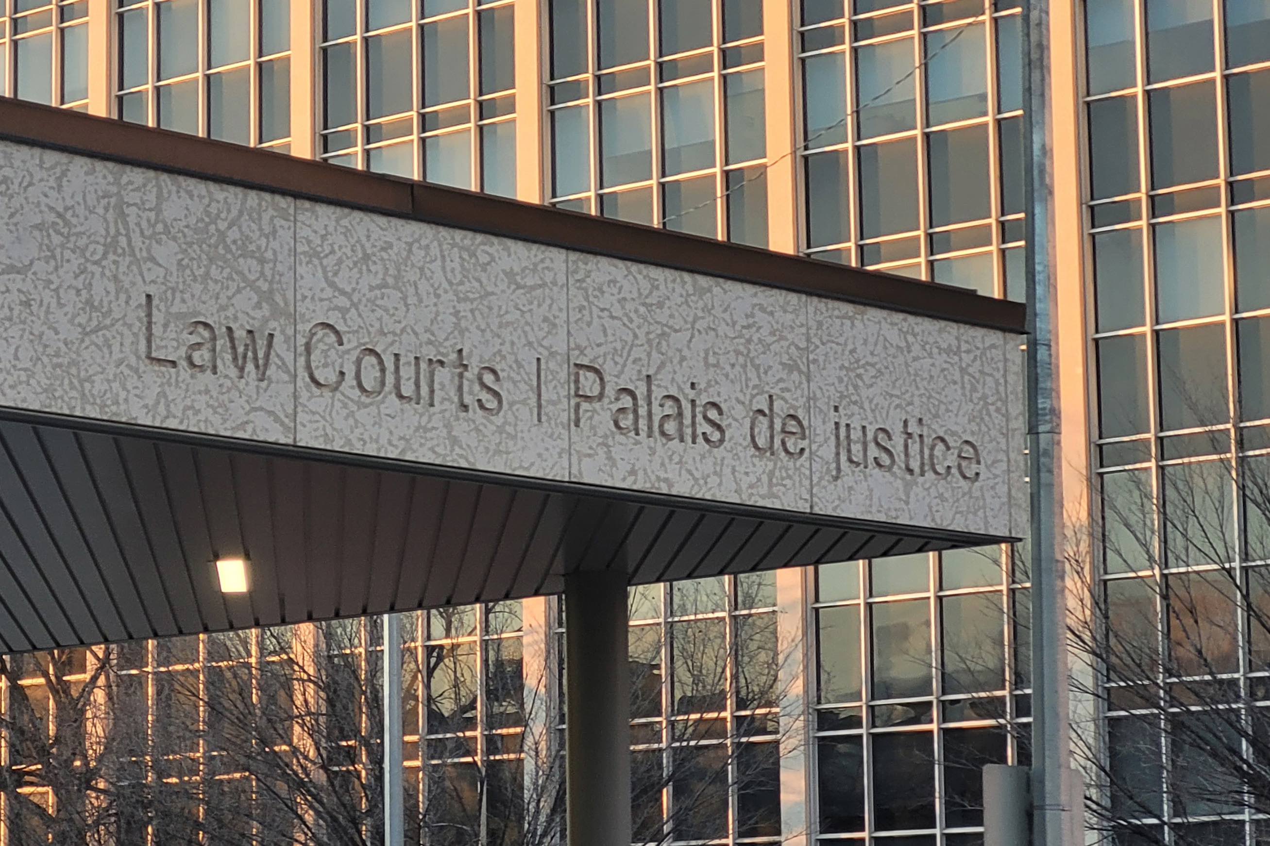 overhang of downtown law courts building against the windows of a building behind in winter sunrise