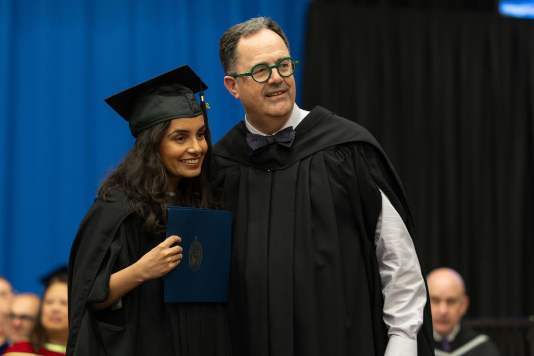 Dr. Guneet Uppal is wearing a graduation cap and gown poses for photo with Dr. Peter Nickerson.