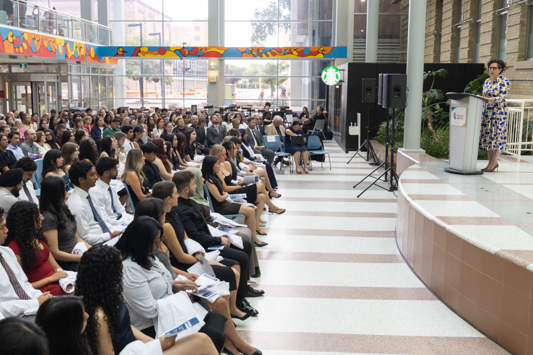 Dr. Anastasia Kelekis-Cholakis speaks at a lectern on a stage in front of a crowd.