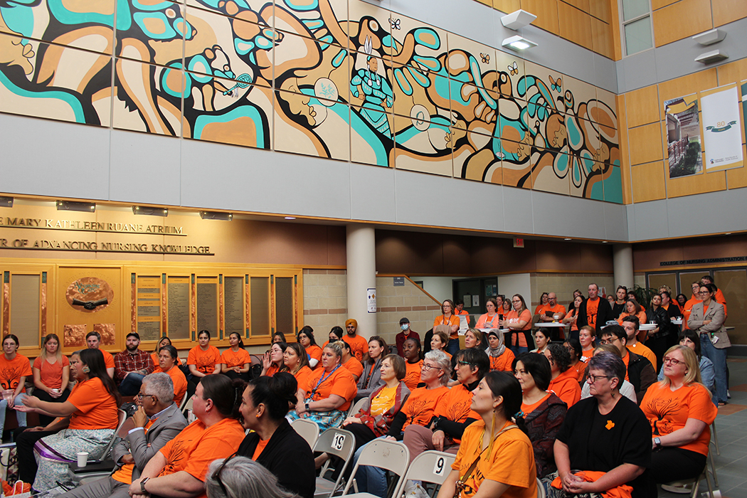 A crowd of people wearing orange shirts gathers inside the Helen Glass Centre for Nursing.