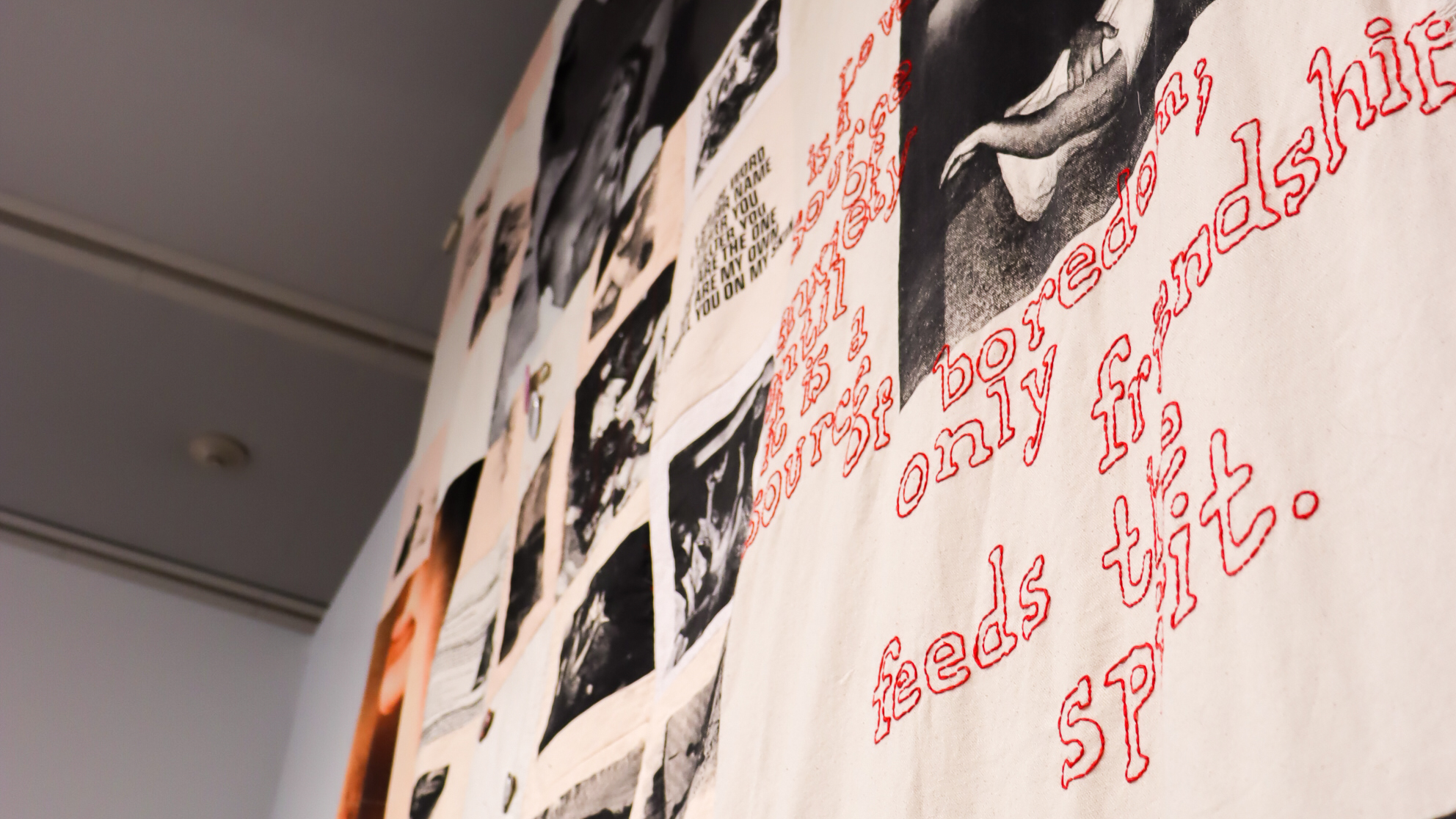 Installation view of Christina Oyawale's Punk Care Commons: fabric banner with collaged photographs and red embroidered text