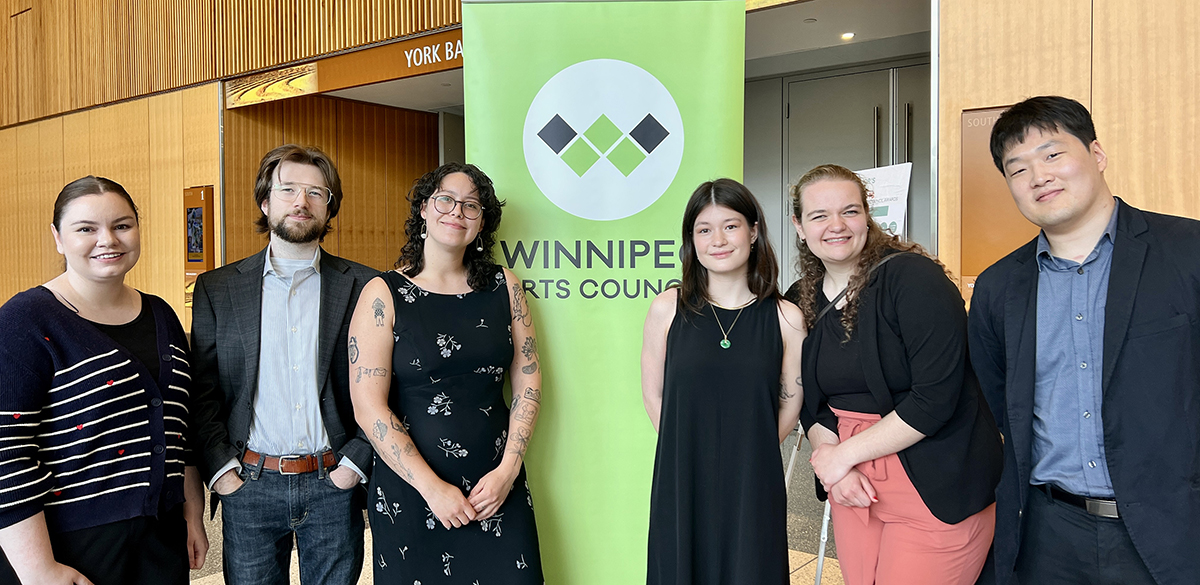 law students stand in front of Winnipeg arts council sign with two arts council staff