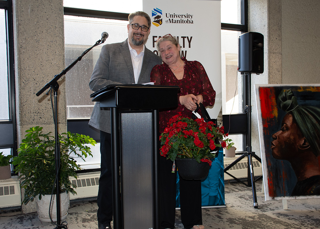 Dr. Richard Jochelson stands beside Elsie Young who holds a basket of red flowers
