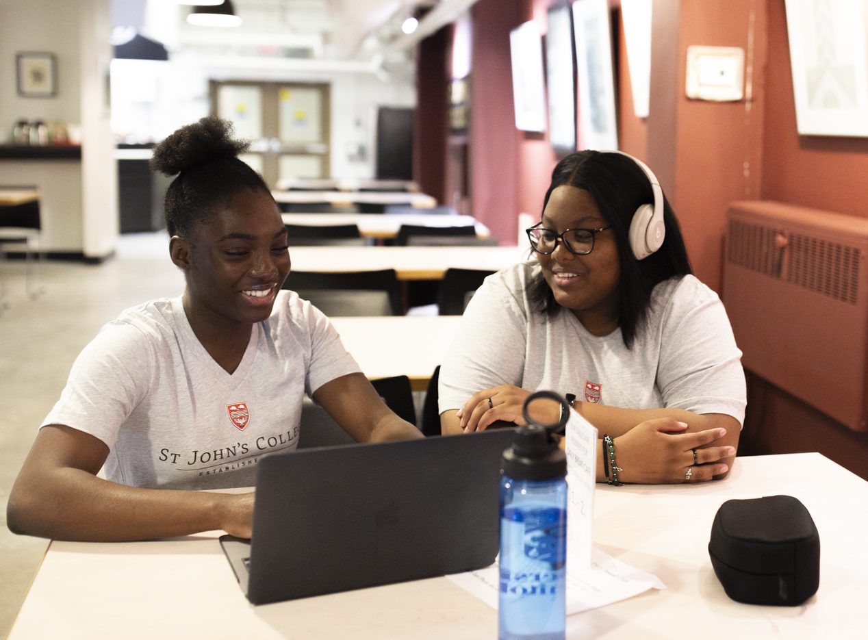 Two female students sitting at a table with a laptop