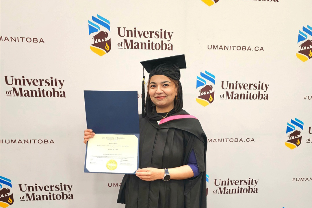 Master of Laws student in cap and gown holding a diploma