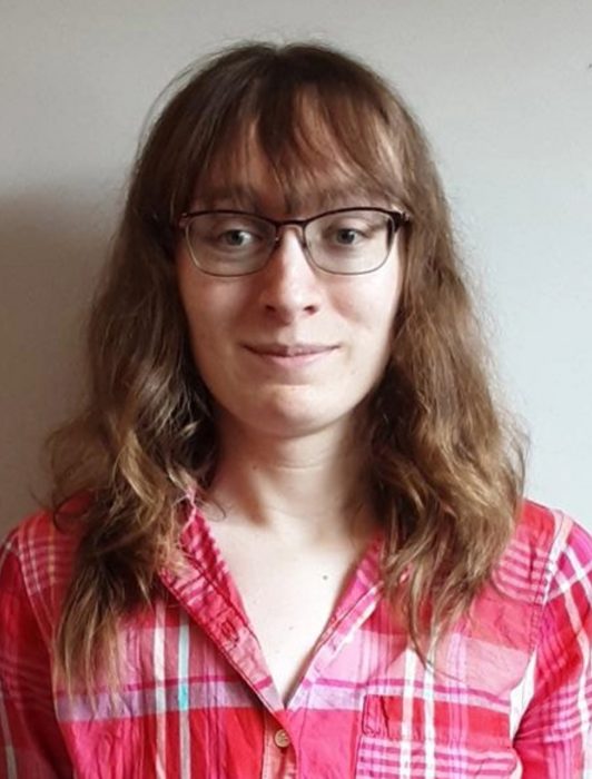 A smiling woman with light brown hair and glasses
