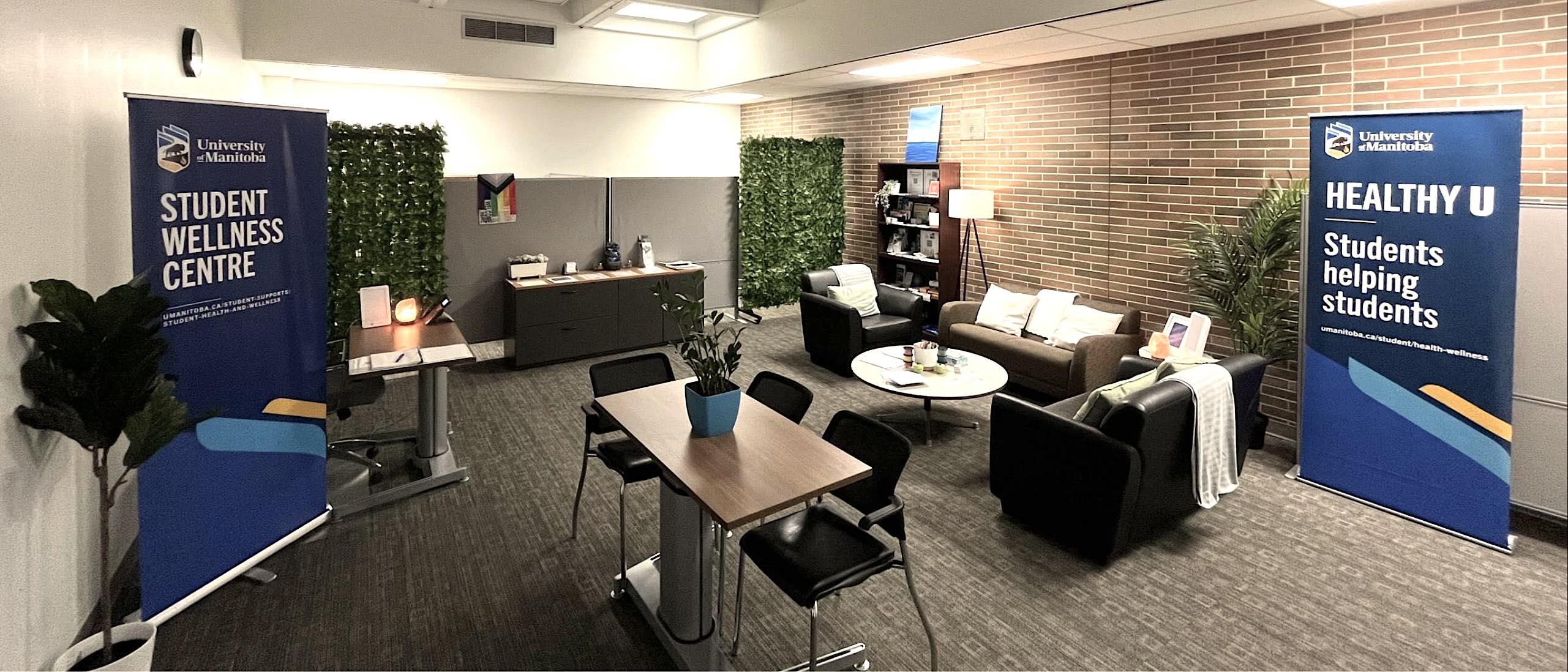 Wide view of cozy open room with sofas, table and chairs, and sign that says Student Wellness Centre.