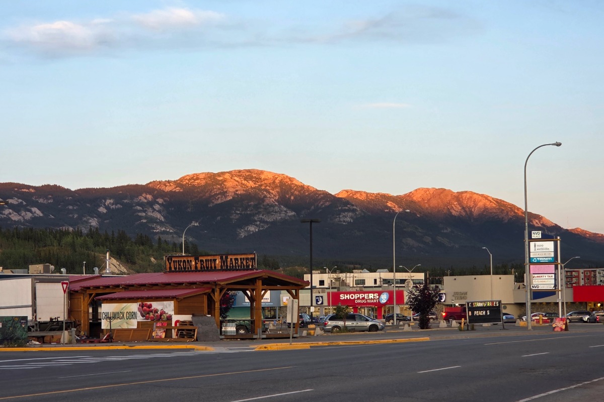 A row of shops in a strip mall set against a backdrop of rugged mountains.