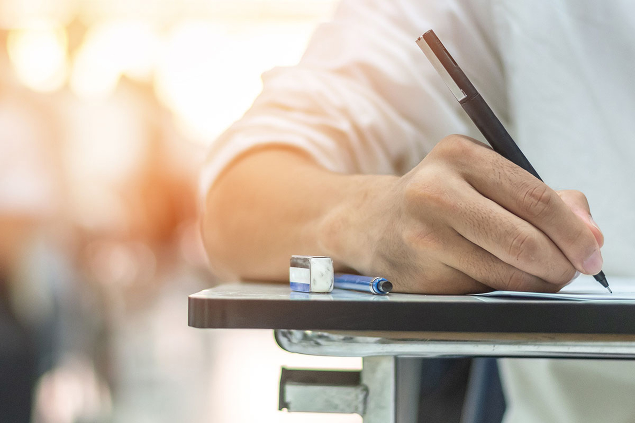 Hand of student at desk wrting an exam