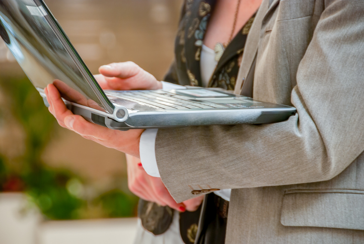 Woman in professional clothing holding a laptop in her arms