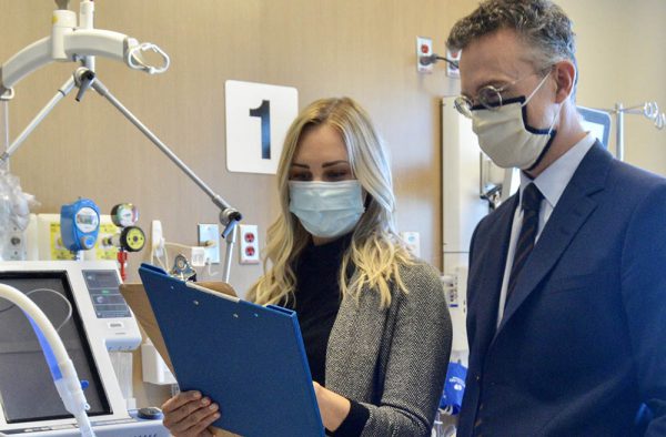 A woman and a man in protective masks review a document.