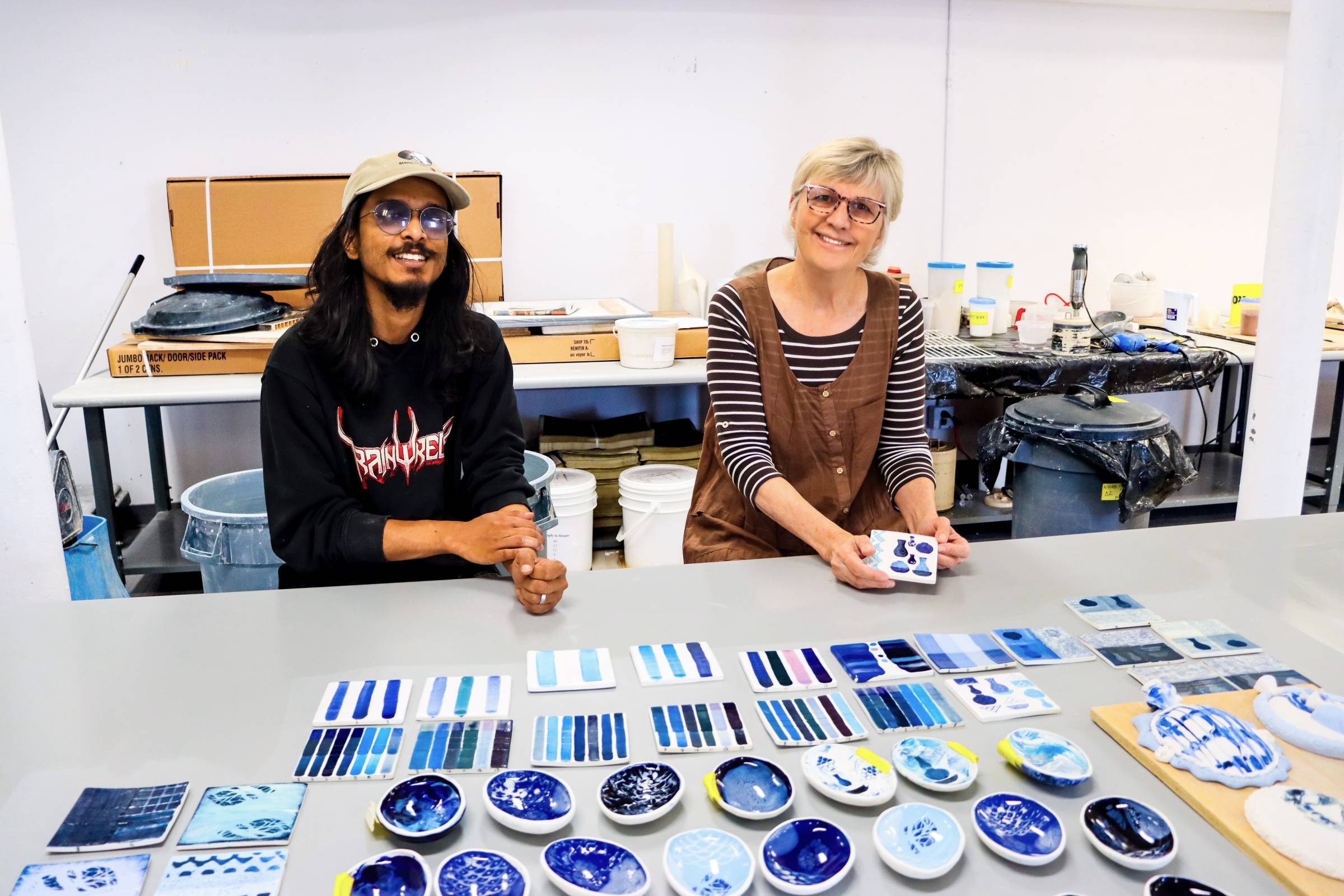 Grace Nickel and Abtahi Hassan showing ceramics pieces with different shades on blue on them.
