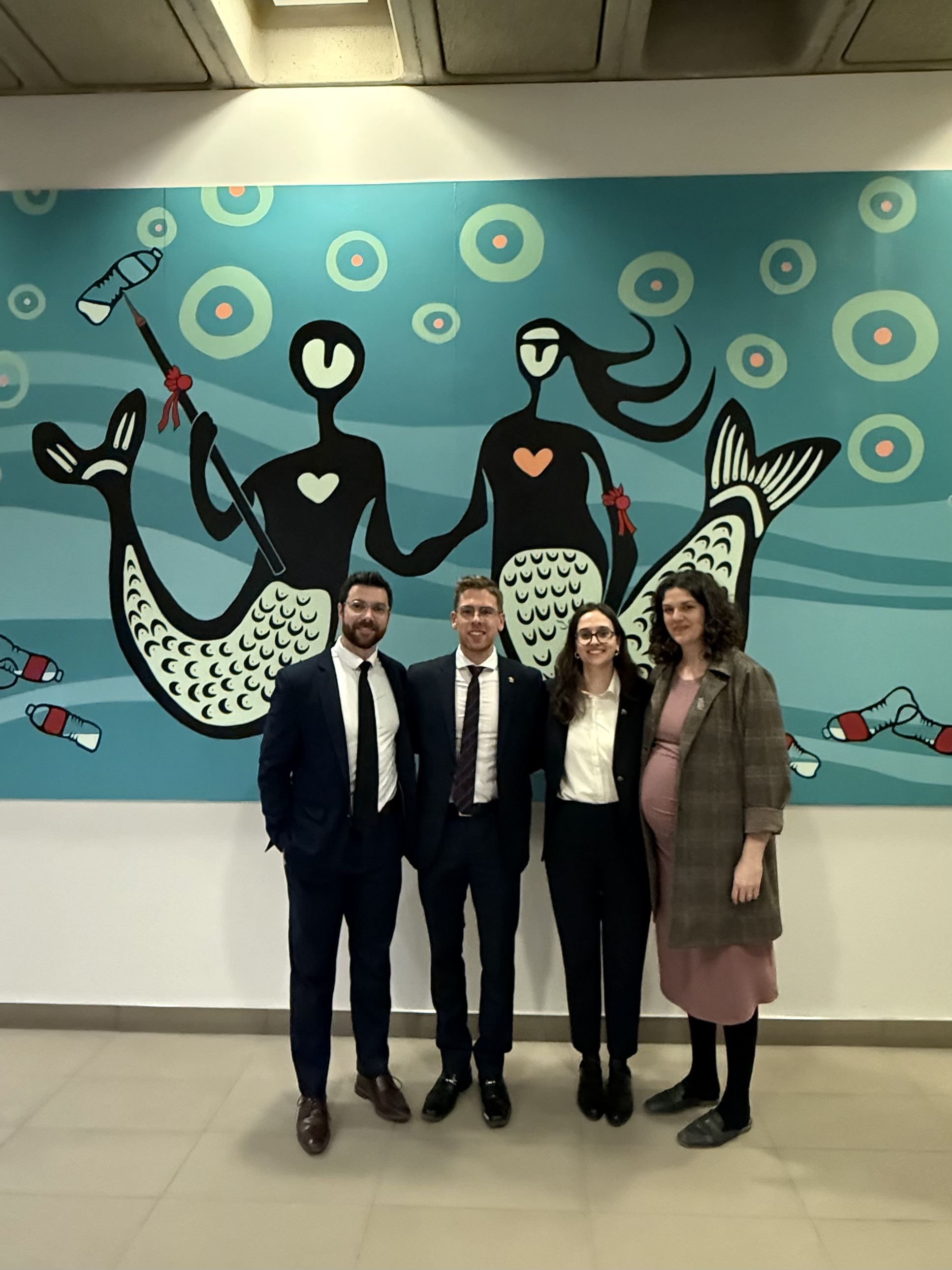 three students and their coach stand in front of a wall mural painting