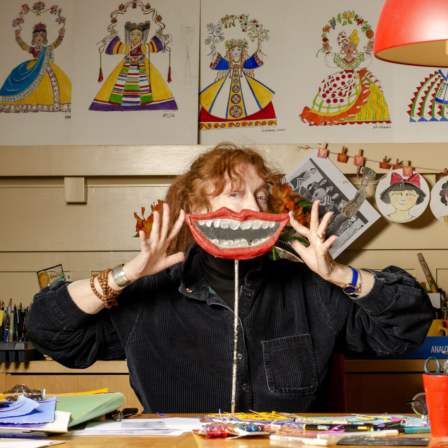 A woman holding a paper mache mouth in front of her own mouth
