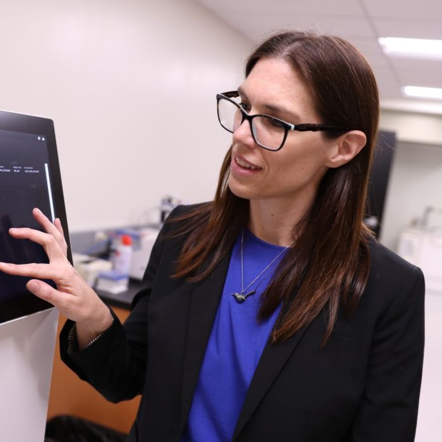Dr. Britt Drögemöller presses a touchscreen on a large machine used for research.