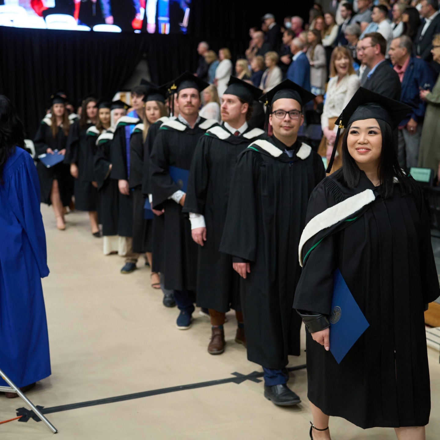 UM graduands lining up in their procession and waiting to be directed to take their seats.