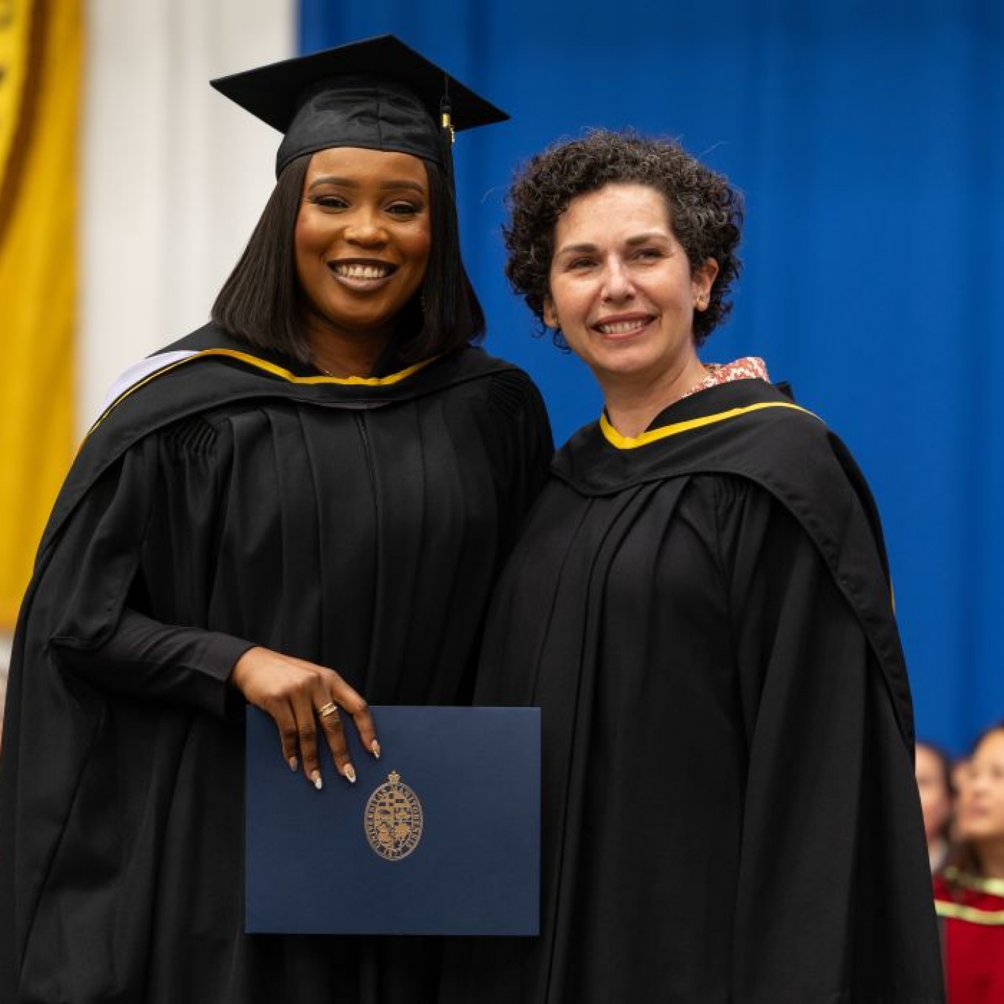 Dr. Sandra Imazenobe wears a graduation cap and gown with Dr. Anastasia Kelekis-Cholakis.