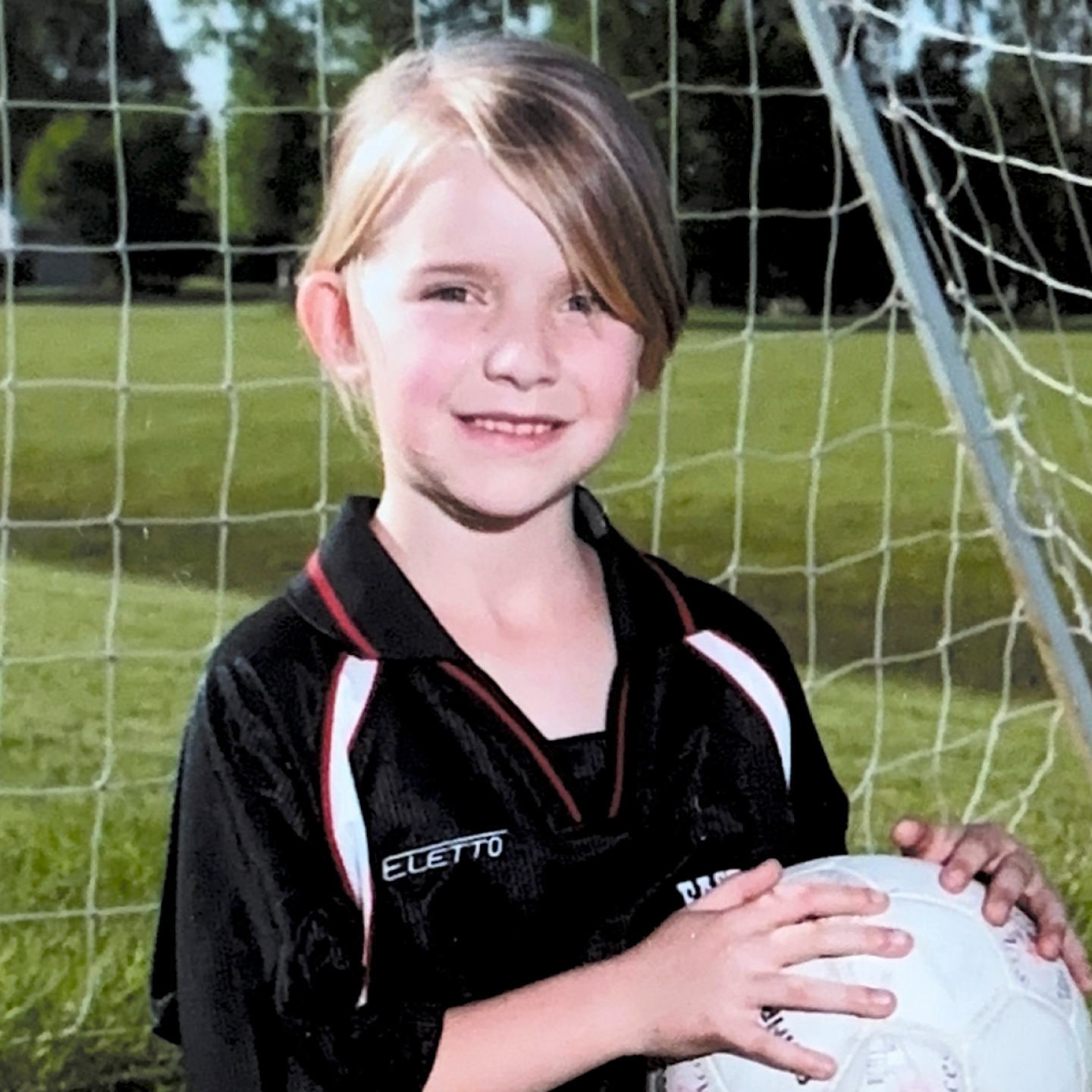 Kaitlyn Klassen as a young girl posing with a soccer ball for a team photo
