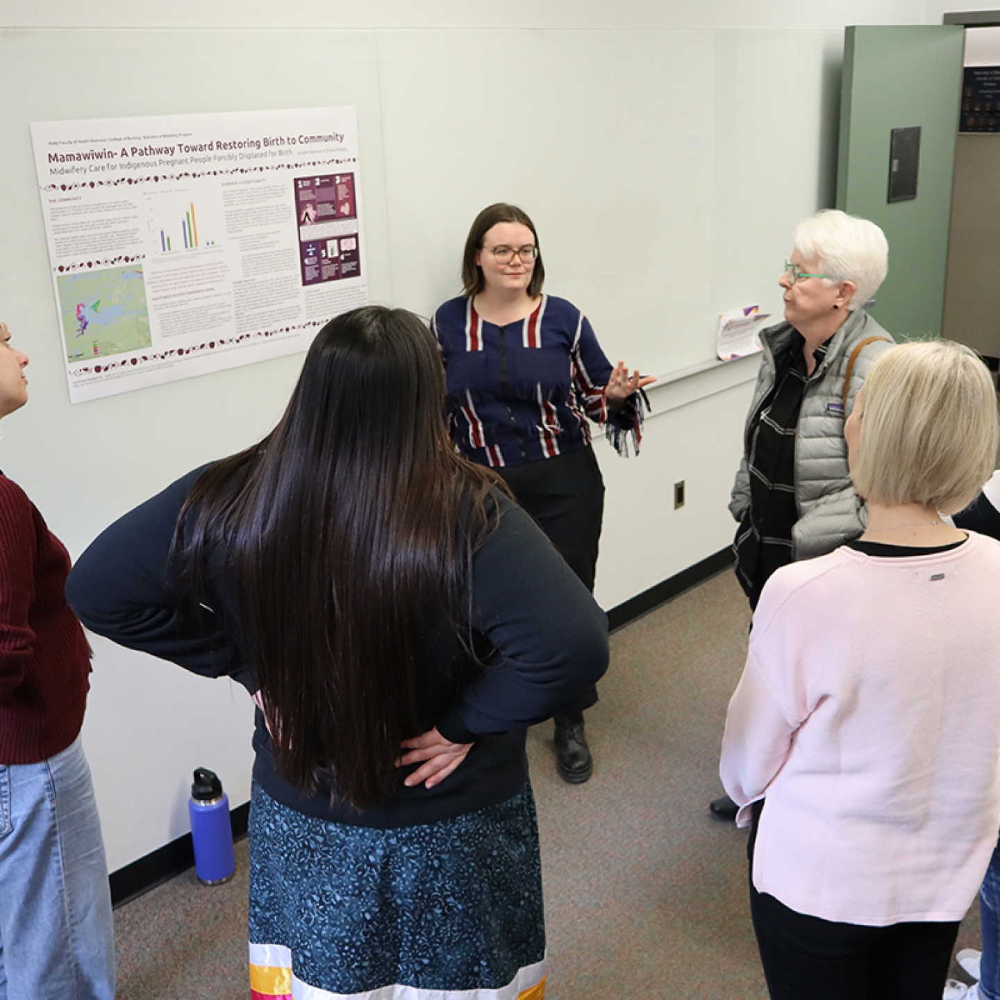 A student explains her poster project to a group of people.