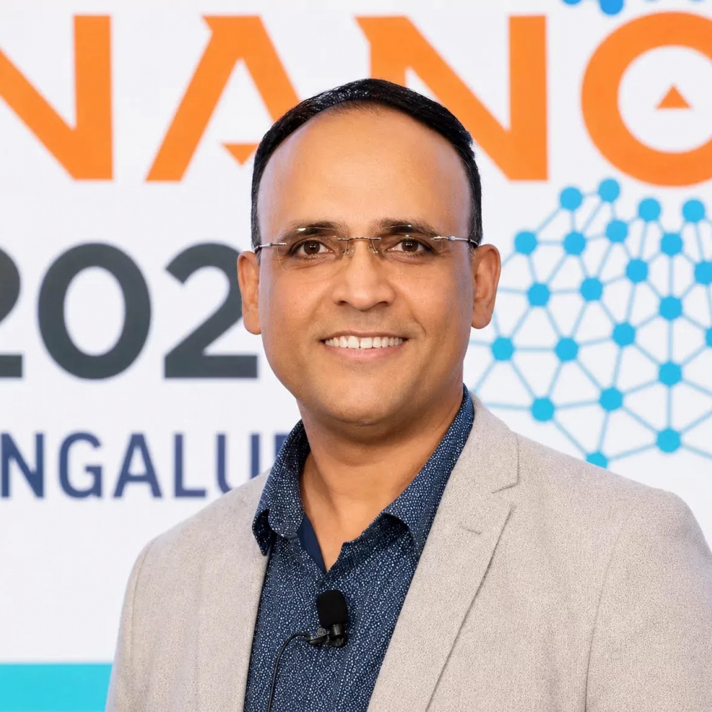 A man smiling in front of a banner.
