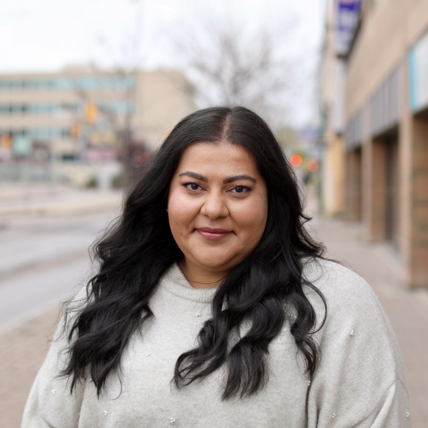 A woman on a street downtown smiles