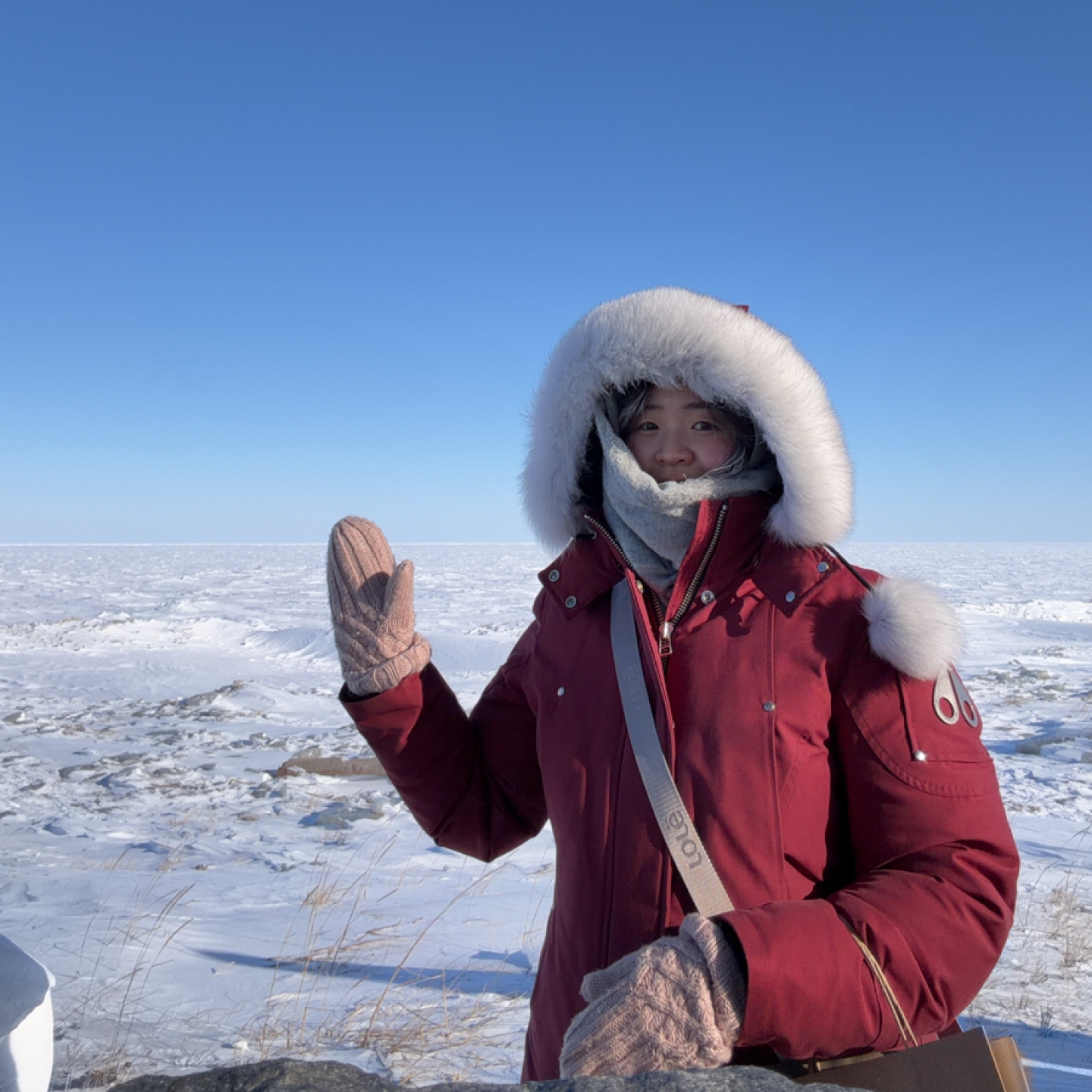 A person poses for the camera in front of a frozen Hudson Bay.