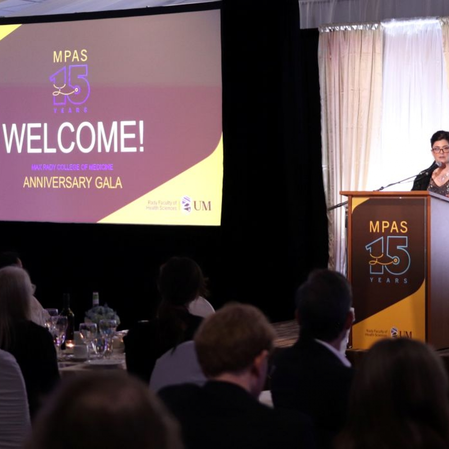 Rebecca Mueller speaks at a lectern in front of a crowd at the MPAS gala. 