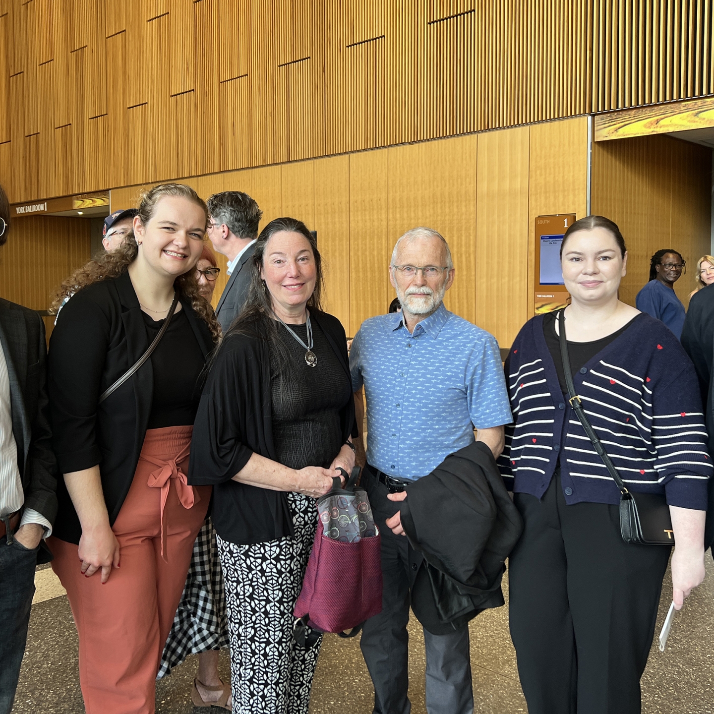 four law students stand on each side of an older couple at Winnipeg's city hall