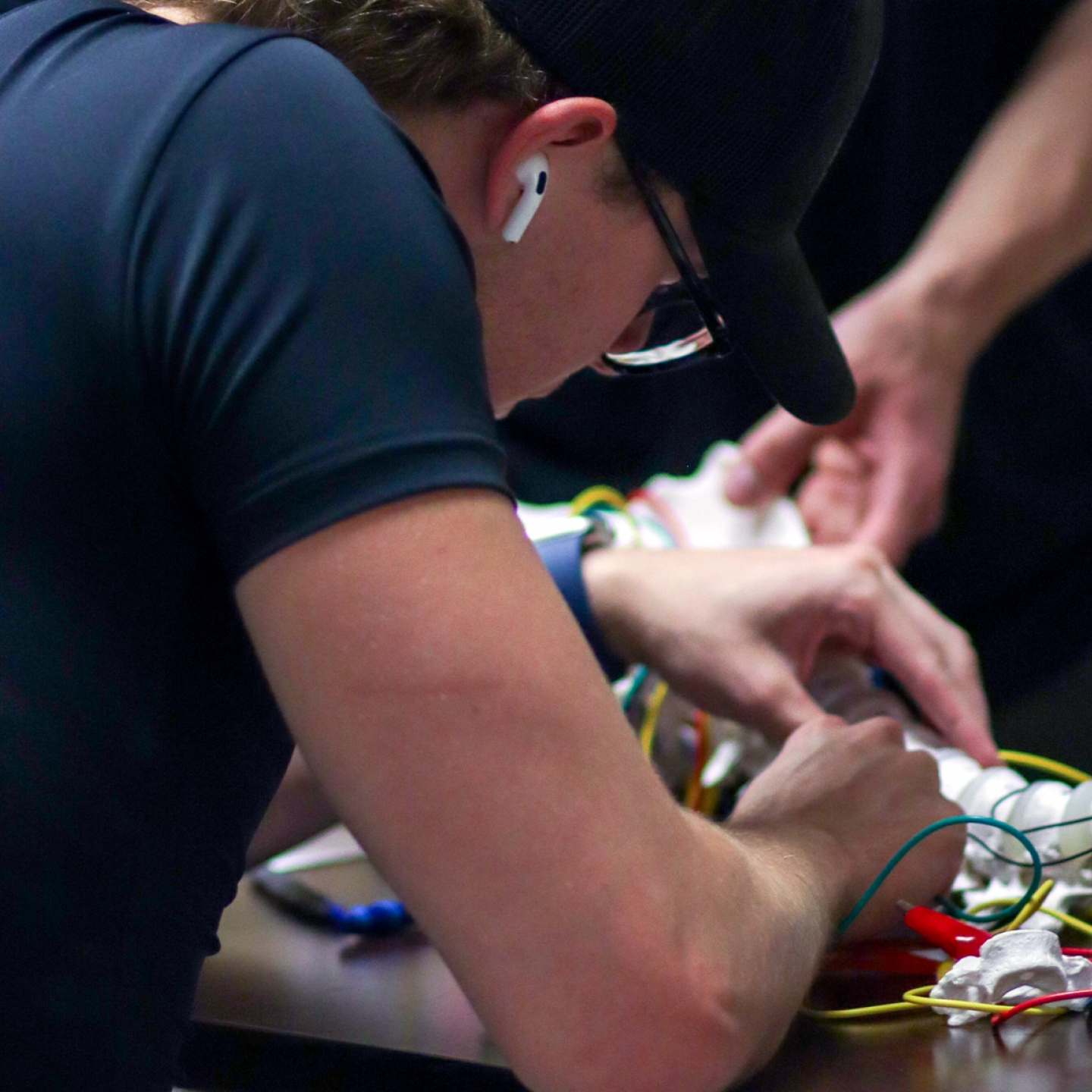 A student works on a model of a spine with electrical wires.