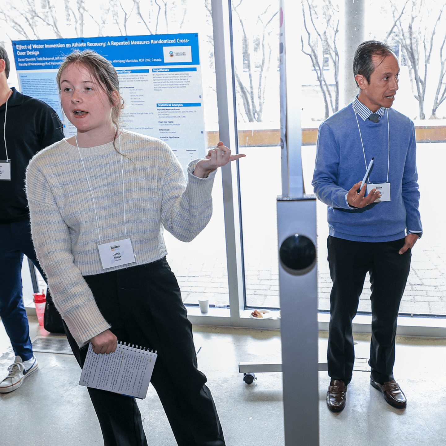 Students explain their posters to participants at Research Day.