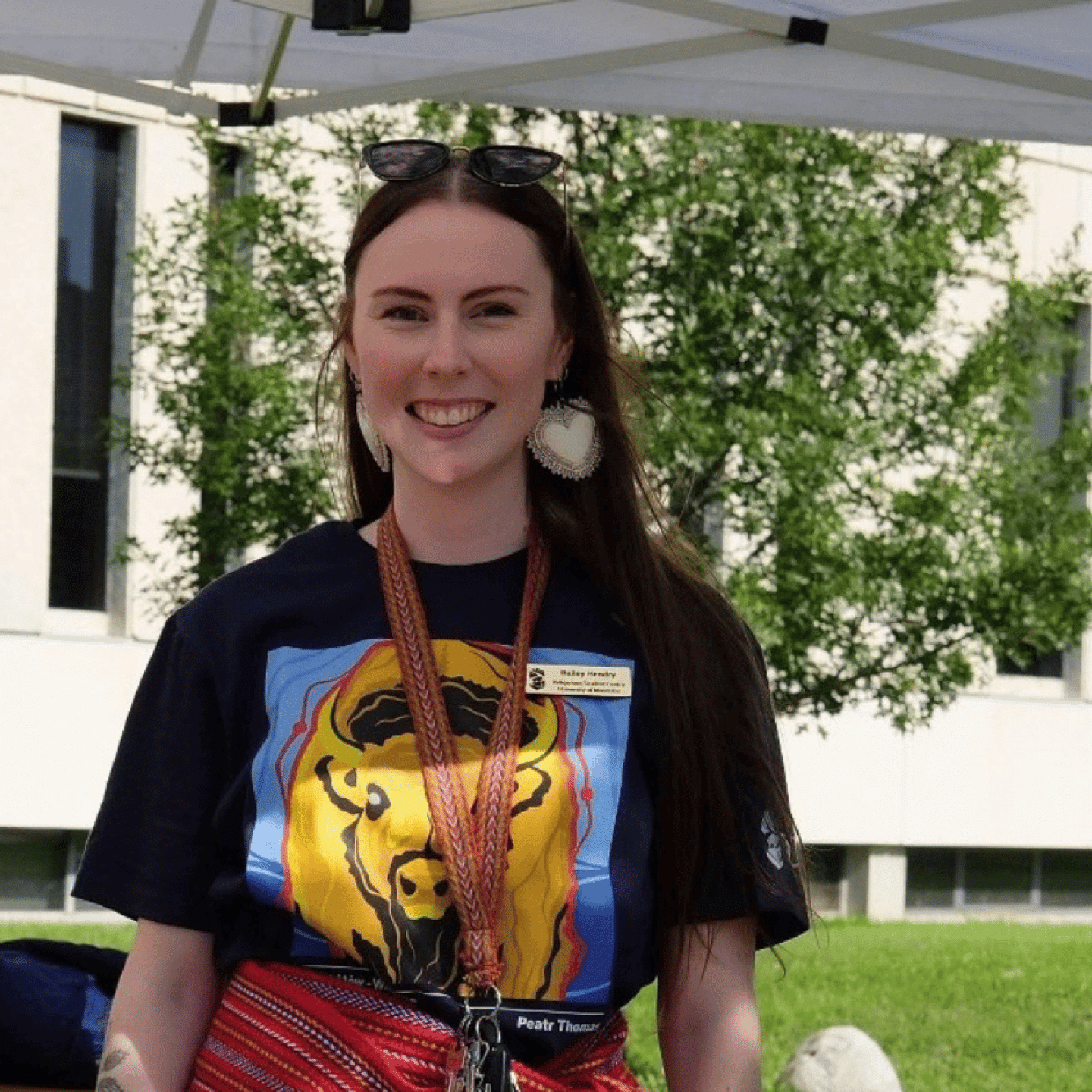 Bailey Pigeau smiles at an outdoor information table during 2025 Indigenous Orietation.