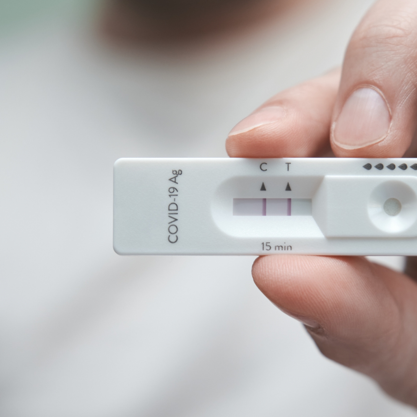 Close-up of a hand holding a positive antigen test for COVID-19. SARS-CoV-2 antigen rapid test kit.