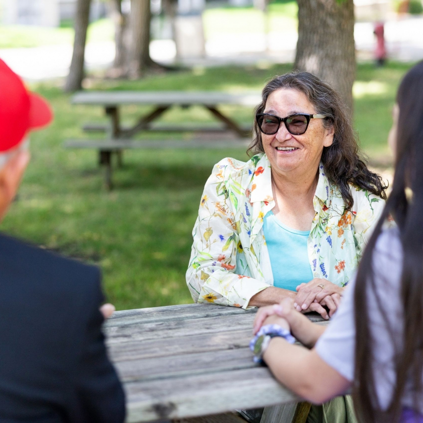 Grandmother-in-Residence sitting outside at a picnic table talking to a student.