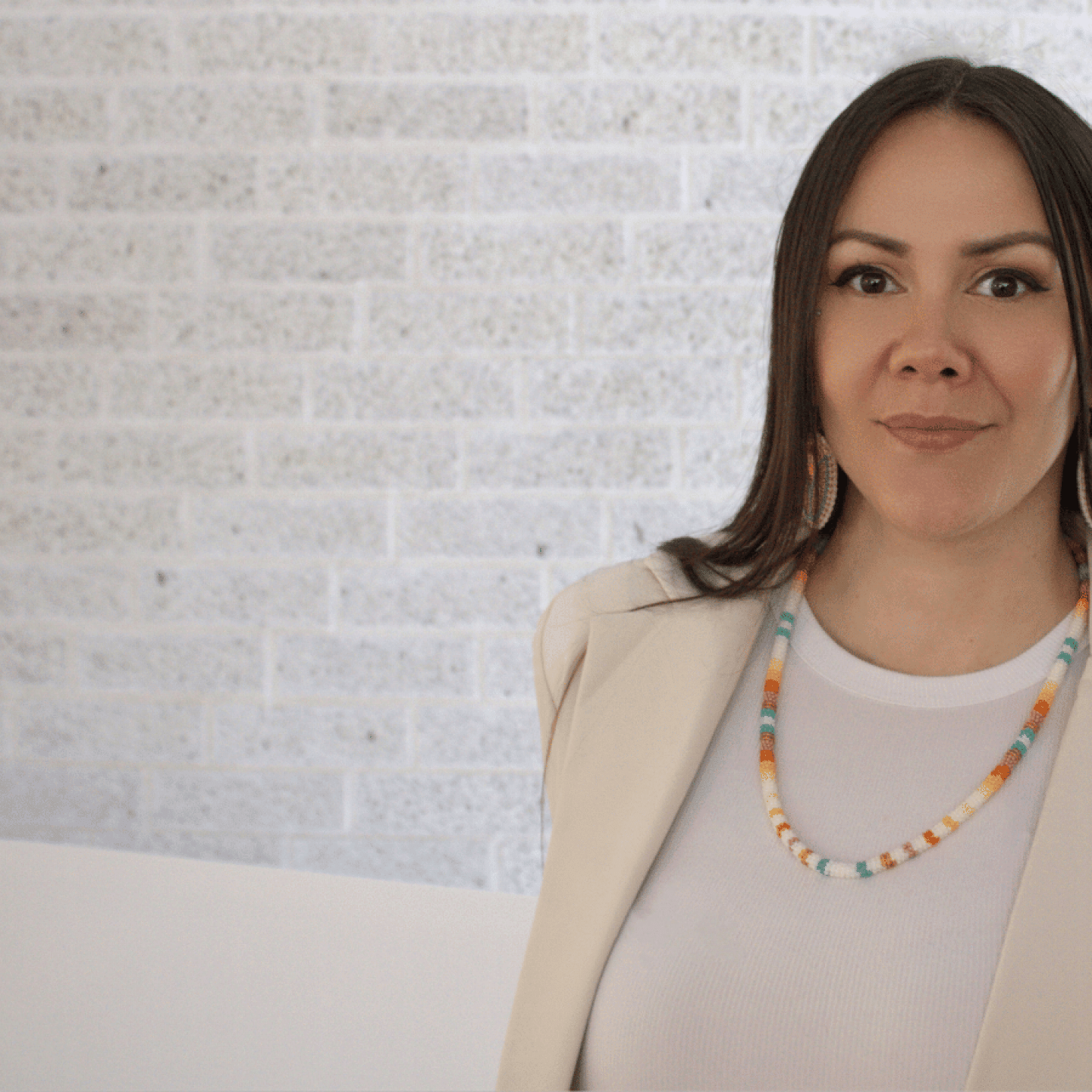 A woman with long dark hair, wearing colourful beaded earrings and a matching necklace.
